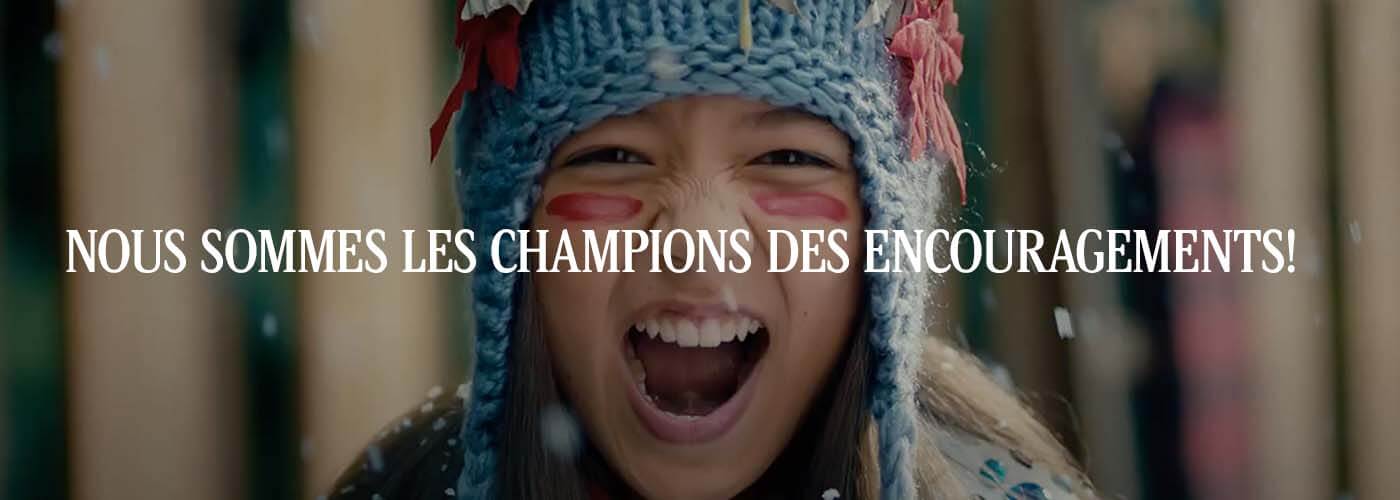 Little girl with blue hat and red warrior paint under her eyes with text across her face saying, "Nous sommes les champions des encouragements!"